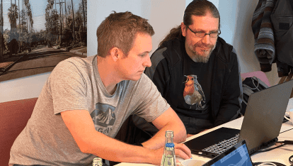 Zwei Entwickler sitzen vor einem Laptop.