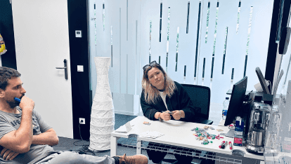 Ein Entwickler und eine Entwicklerin sitzen nachdenklich vor einem Whiteboard.