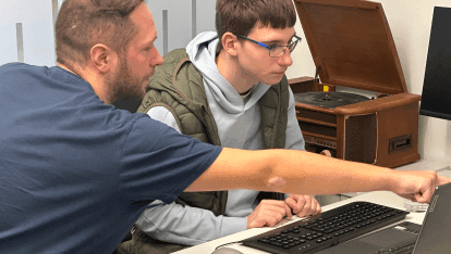 Ein Senior-Entwickler zeigt einem Junior-Entwickler etwas am Laptop.  